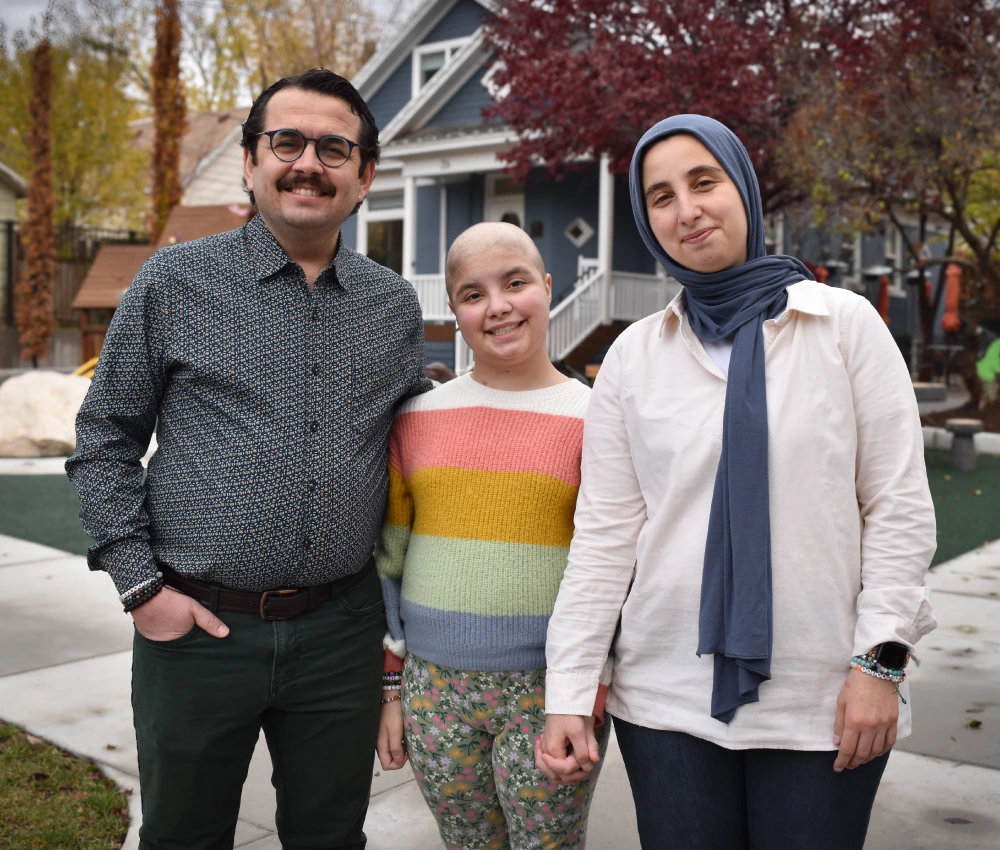 mother and father with young daughter smiling and standing closely together