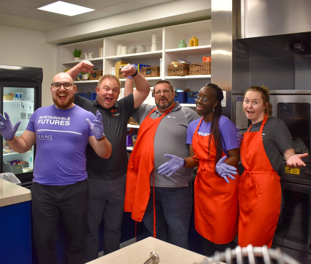 group of volunteers smiling in the kitchen as they prepare a meal for our families