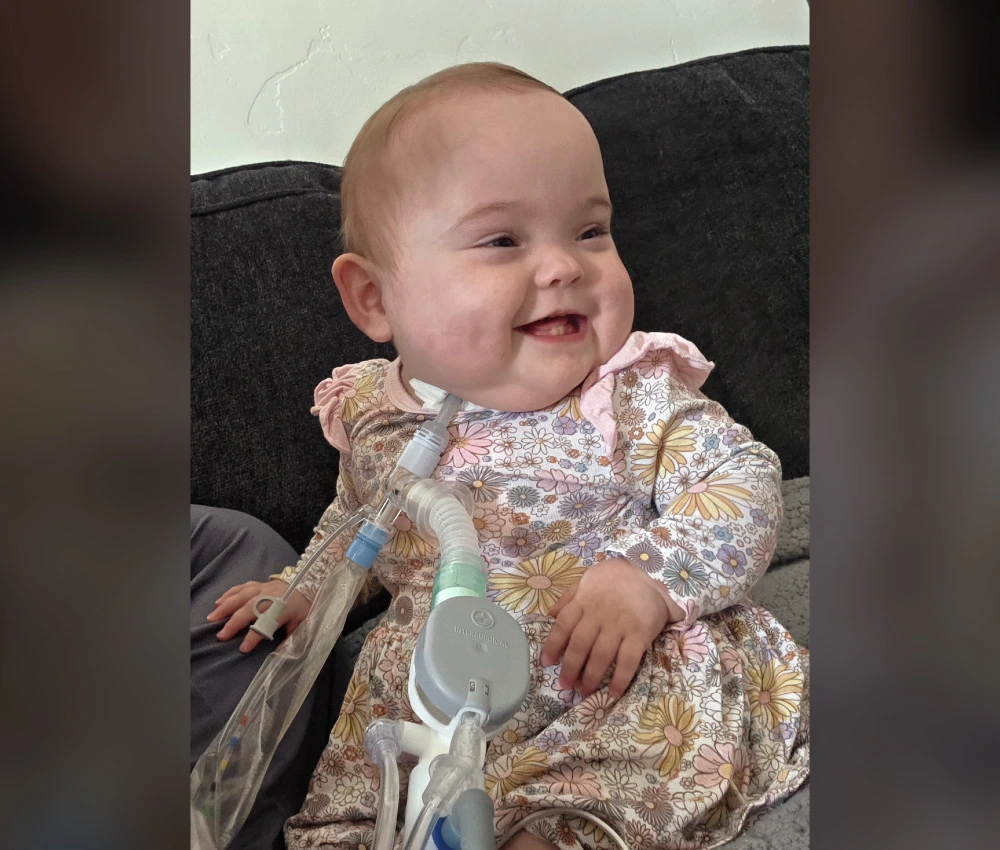 Baby girl kaya Lynn smiling with medical assistance devices near her