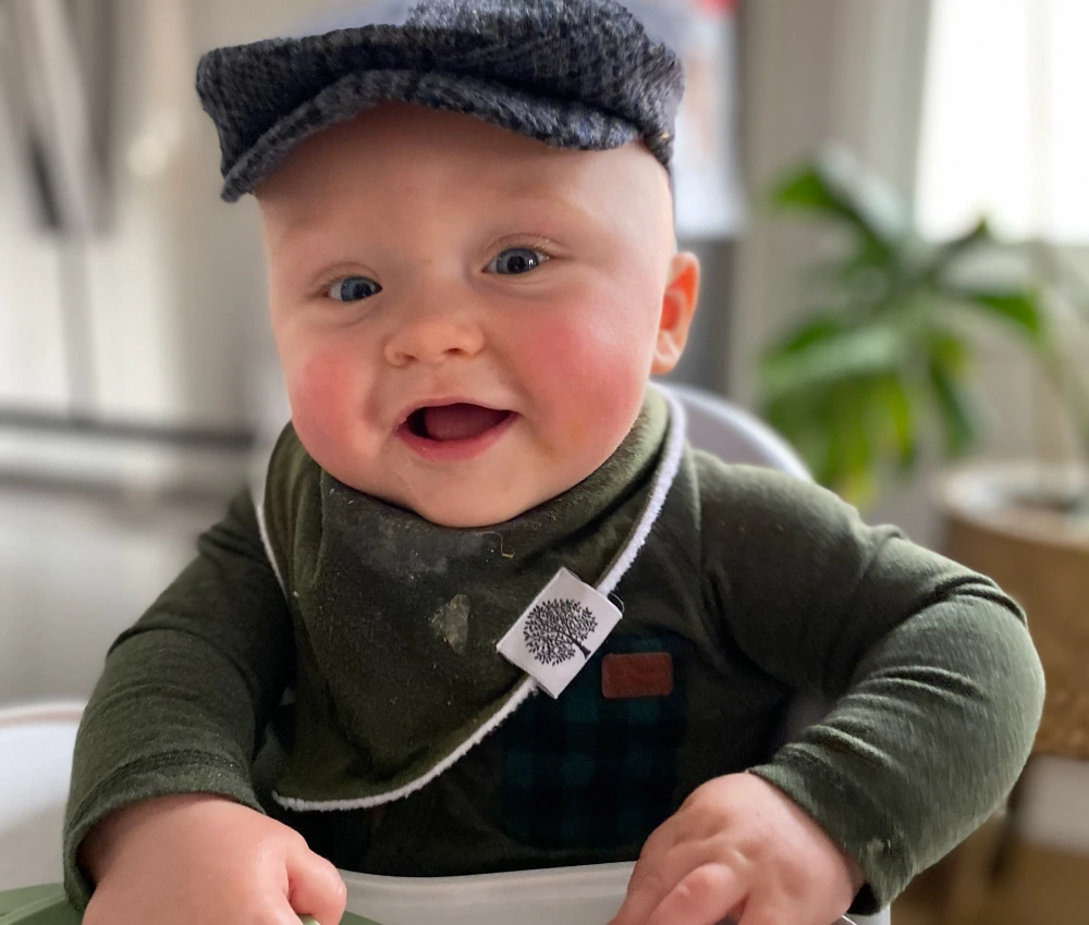 baby boy Rudy with a plaid cap on and green shirt