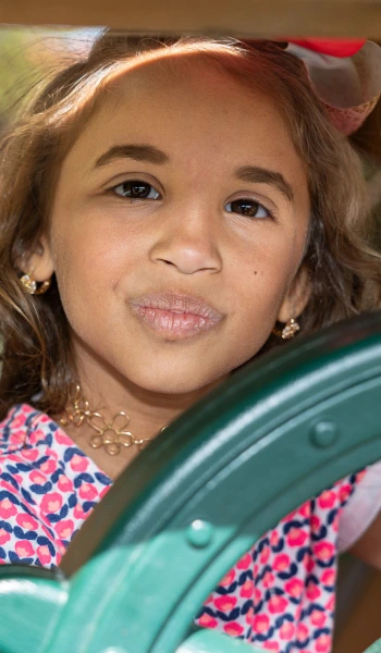 young girl playing with ship's wheel on playground